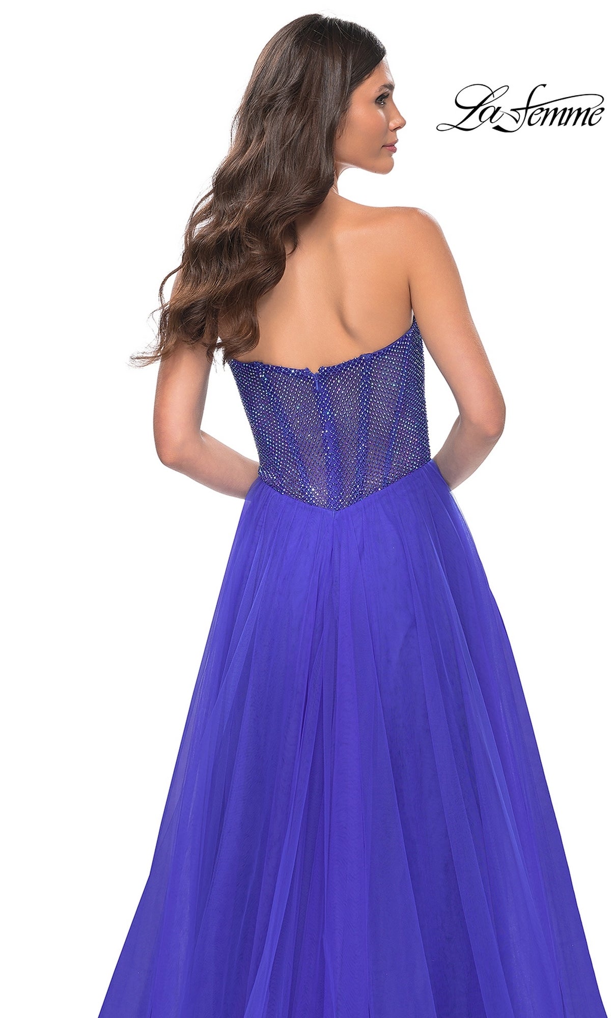 A woman with long brown hair is shown from the back wearing the La Femme Strapless Long A-Line Prom Dress 32216 in royal blue, featuring a beaded bodice. The